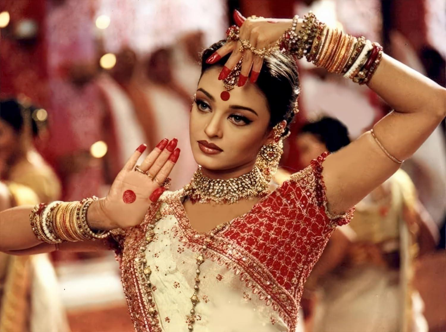 Eine indische Frau in traditioneller Kleidung posiert. Sie trägt einen roten Punkt, Schmuck und roten Nagellack. Sie befindet sich in einer Tanzpose.