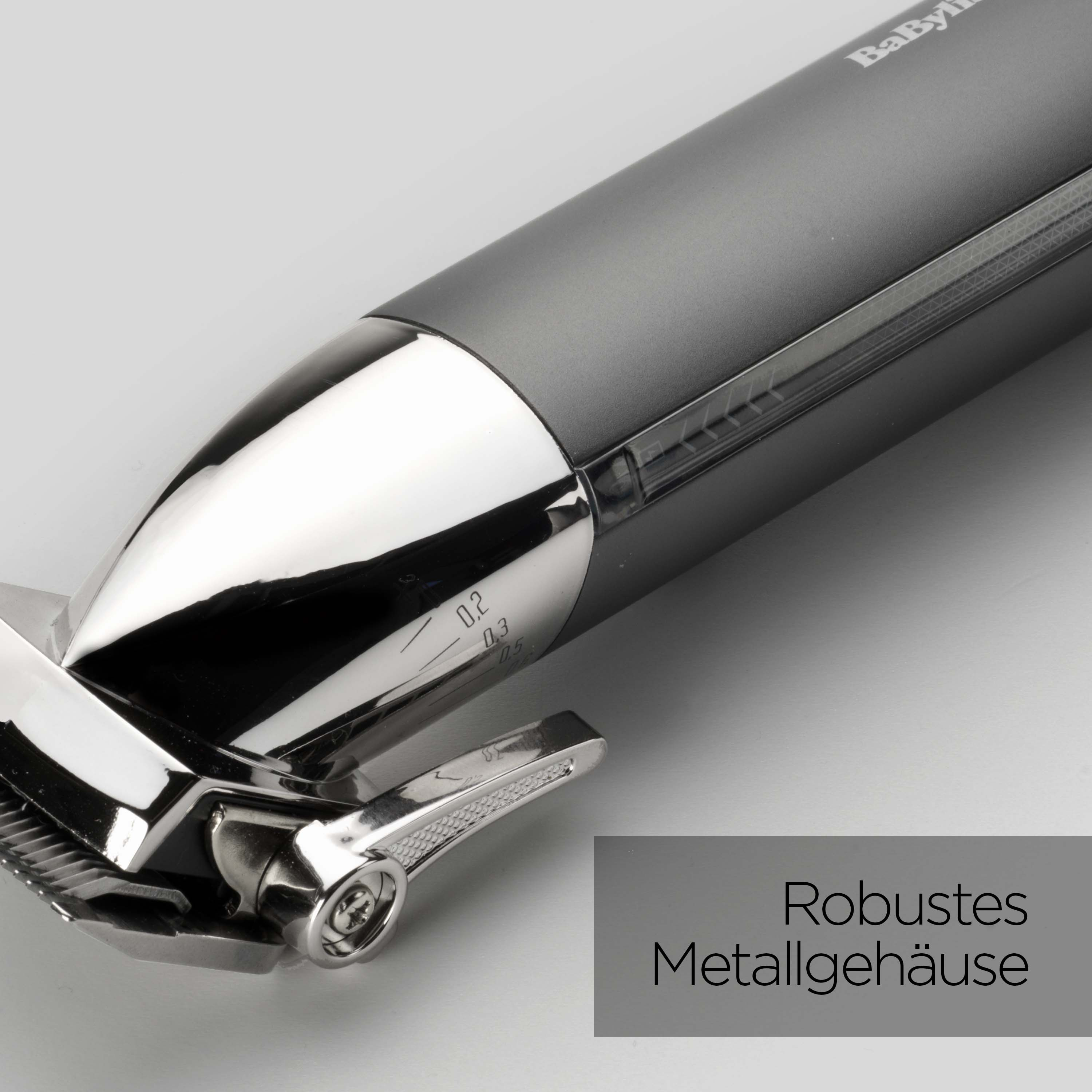 Nahaufnahme eines Babyliss-Haarschneiders. Er hat einen dunkelgrauen Körper, glänzende Silberteile und eine Klinge. Text: 'Robustes Metallgehäuse'.