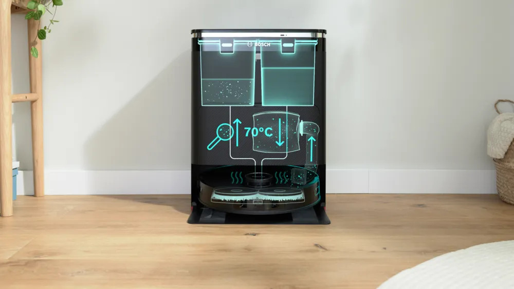 Czarny robot sprzątający Bosch z diagramami pokazującymi ogrzewanie wody do 70°C. Stoi na drewnianej podłodze przed białą ścianą.