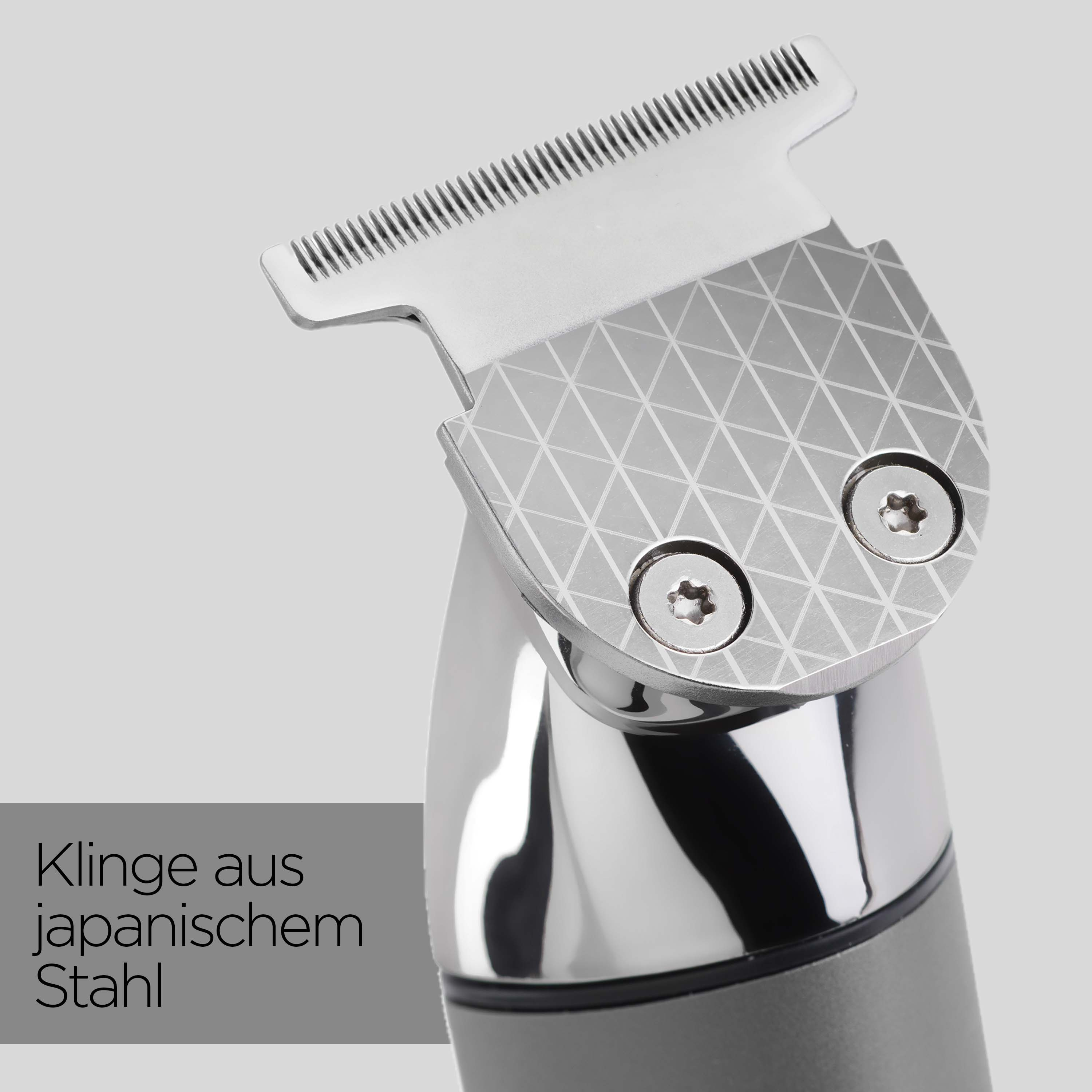 Nahaufnahme eines silbernen Haarschneiders. Klinge oben, mit Muster. Der Griff ist schwarz und grau.