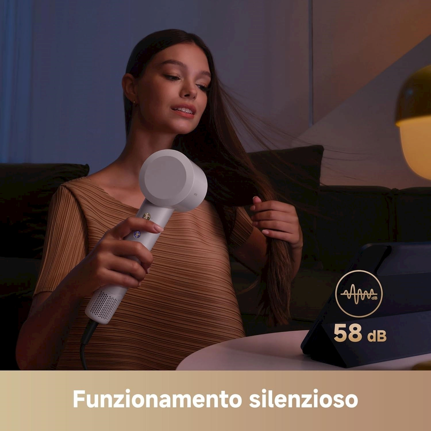 Donna che usa un asciugacapelli bianco. Un tablet mostra 58 dB. Testo: Funzionamento silenzioso.