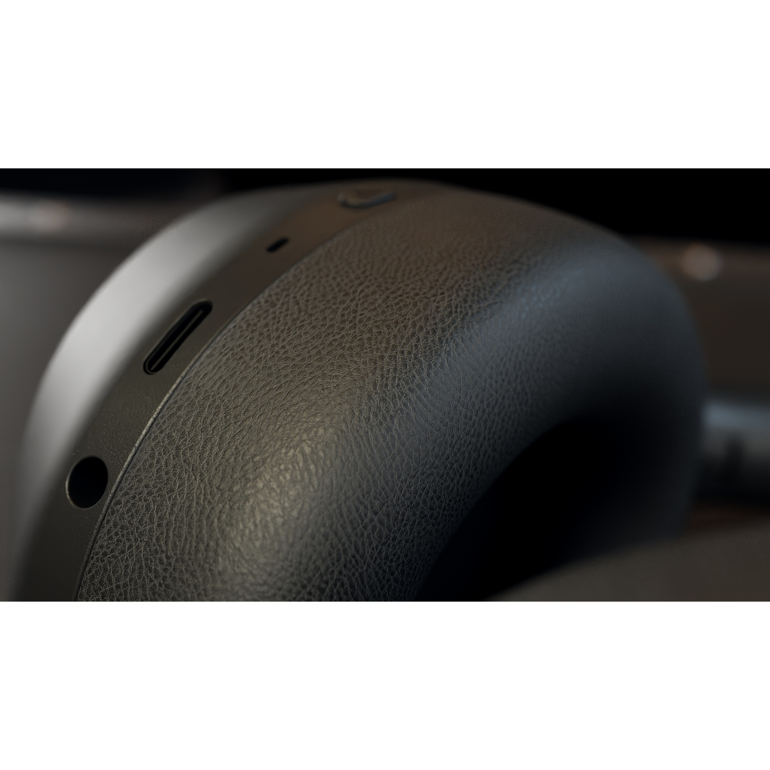 Primo piano di cuffie nere. La texture simile alla pelle è visibile sul padiglione. Sono presenti anche una porta USB-C e un piccolo foro.