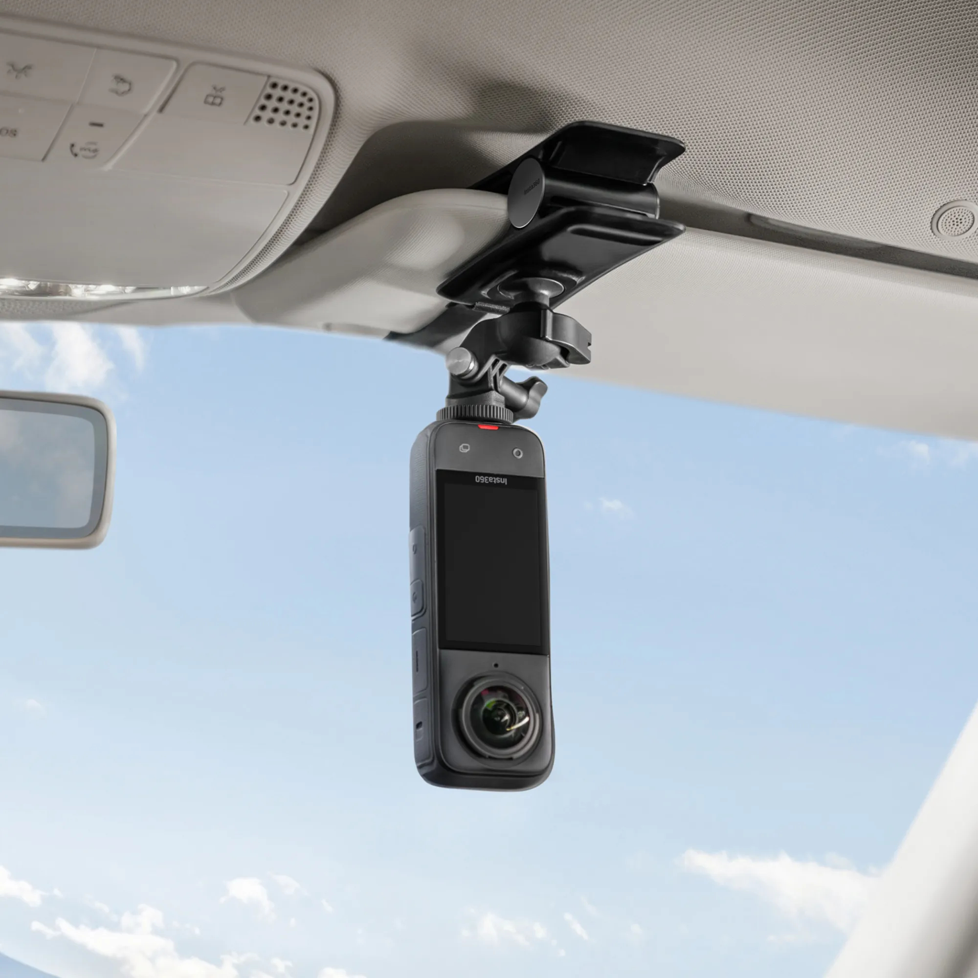 Eine schwarze Action-Kamera ist im Inneren eines Autos montiert. Sie ist an der Decke befestigt und zeigt nach unten. Der Hintergrund ist der Himmel.