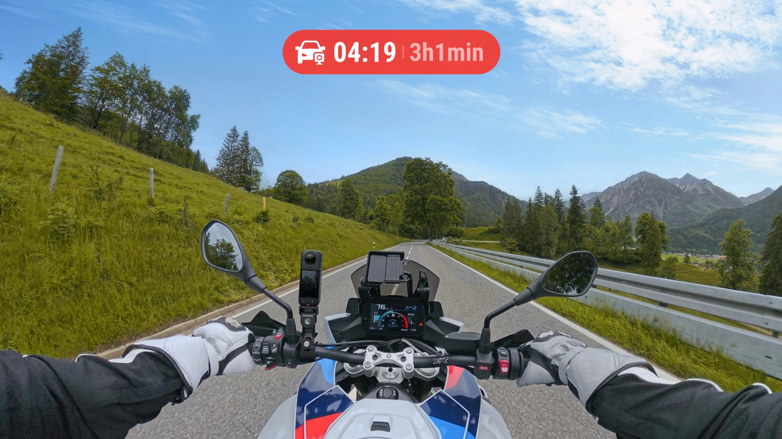 Motorradfahrt auf einer Straße durch grüne Hügel und Berge. Sicht des Fahrers mit Tachometer und Zeitanzeige.