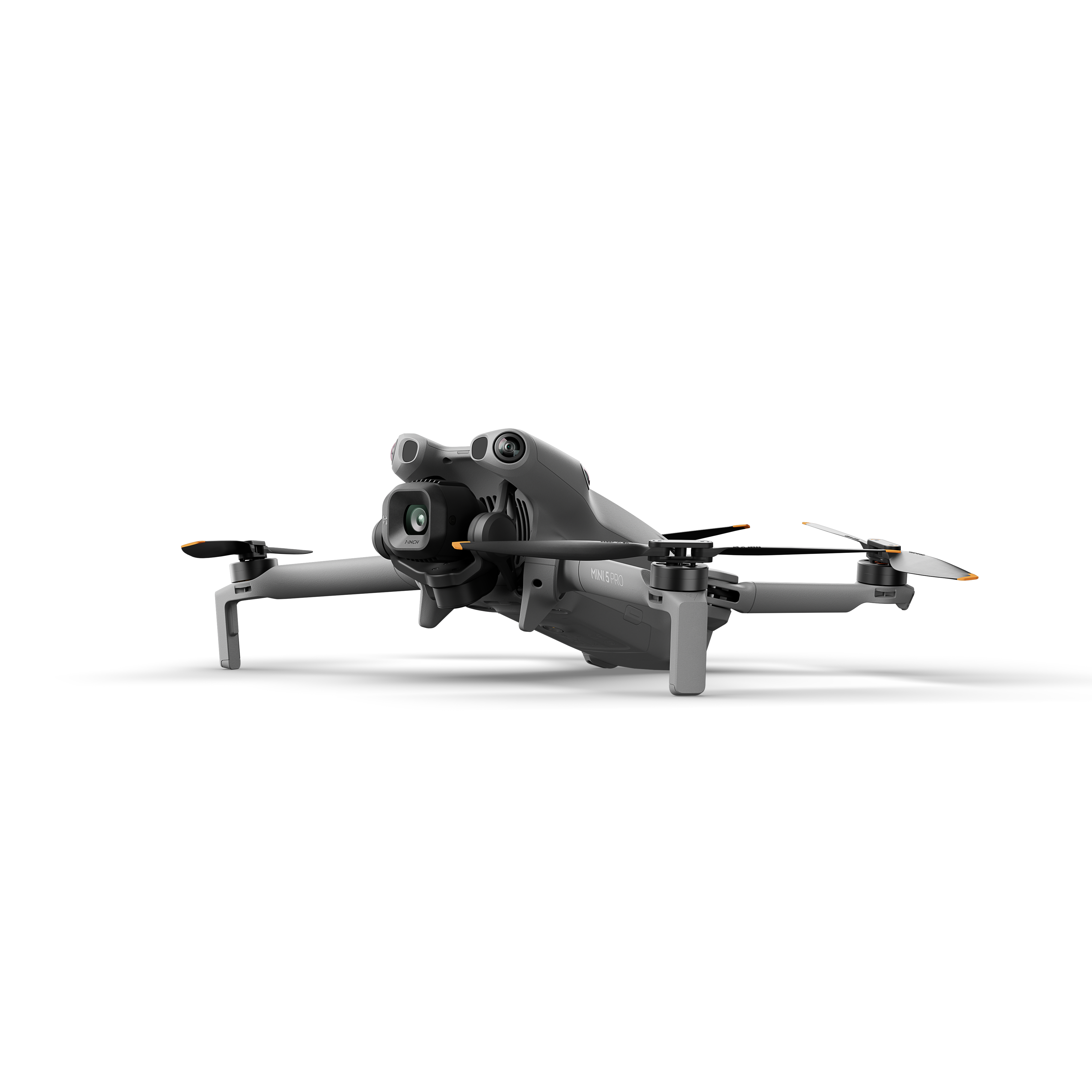 Beyaz zemin üzerinde dört pervaneli, kameralı ve iniş takımlı gri bir drone.
