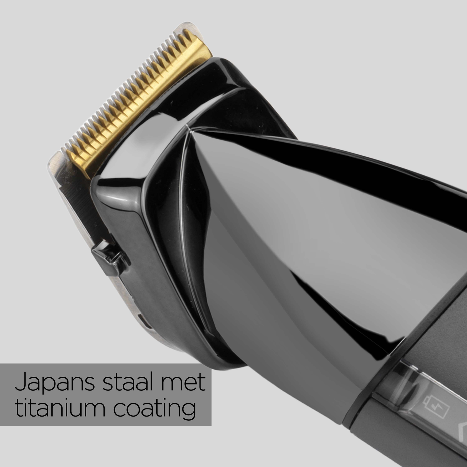 A close-up of a black hair clipper with a gold blade. The clipper is angled, showcasing the blade and the black casing against a grey backdrop.