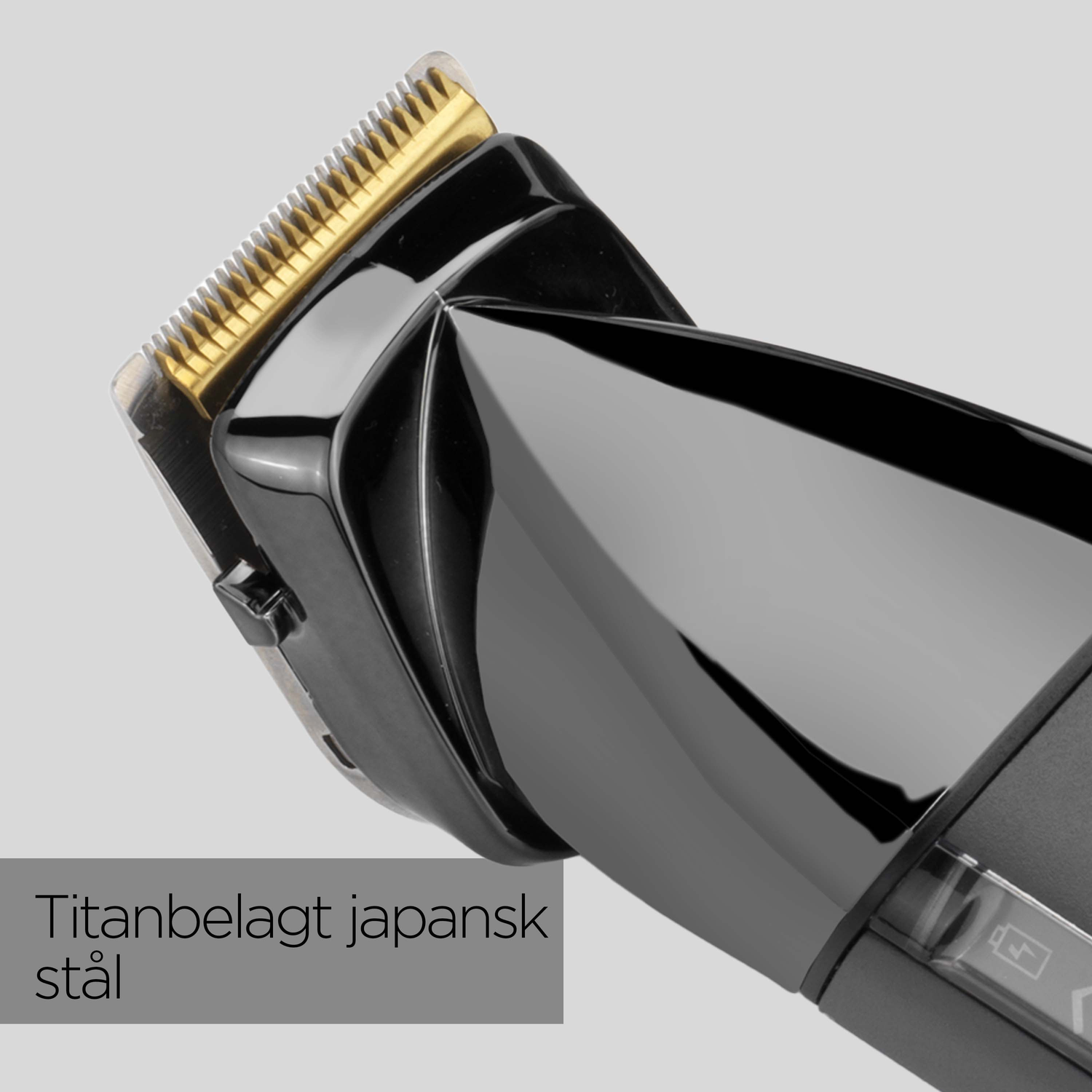 Close-up of a black and gold hair clipper. The blade is gold, and the body is black. The text says 'Titanium coated Japanese steel'.