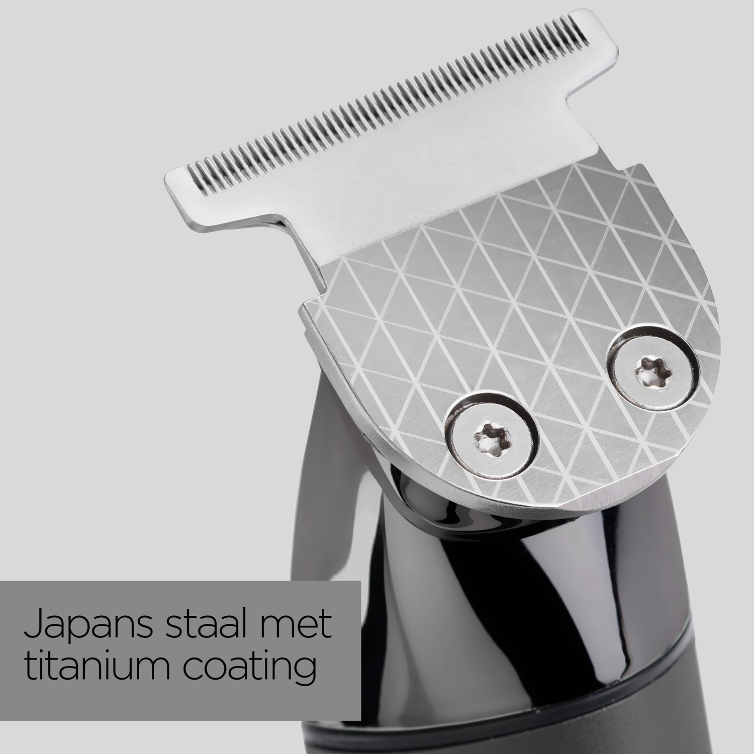 Close-up of a silver and black hair clipper head with intricate geometric pattern. The clipper head is made of Japanese steel with titanium coating.