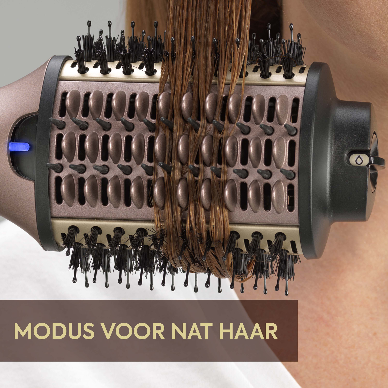 A hair styling tool with wet hair. The tool has a cylindrical brush head with black bristles and brown hair is being styled.