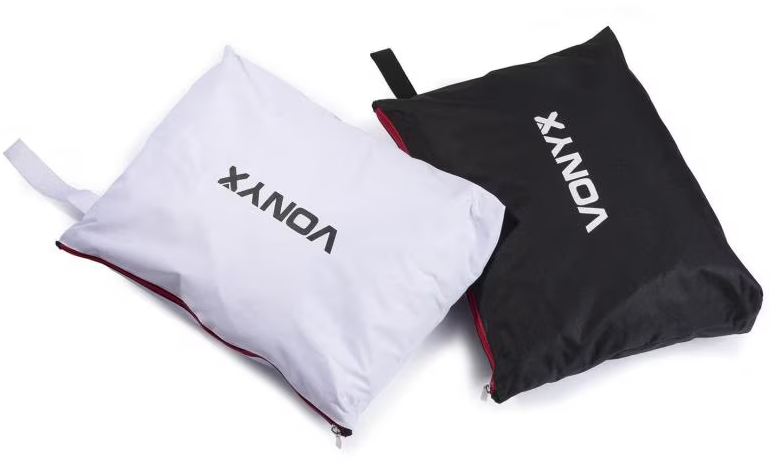 Deux sacs en tissu, un blanc et un noir, tous deux avec le mot 'VONYX' imprimé. Ils ont un passepoil rouge sur les bords.