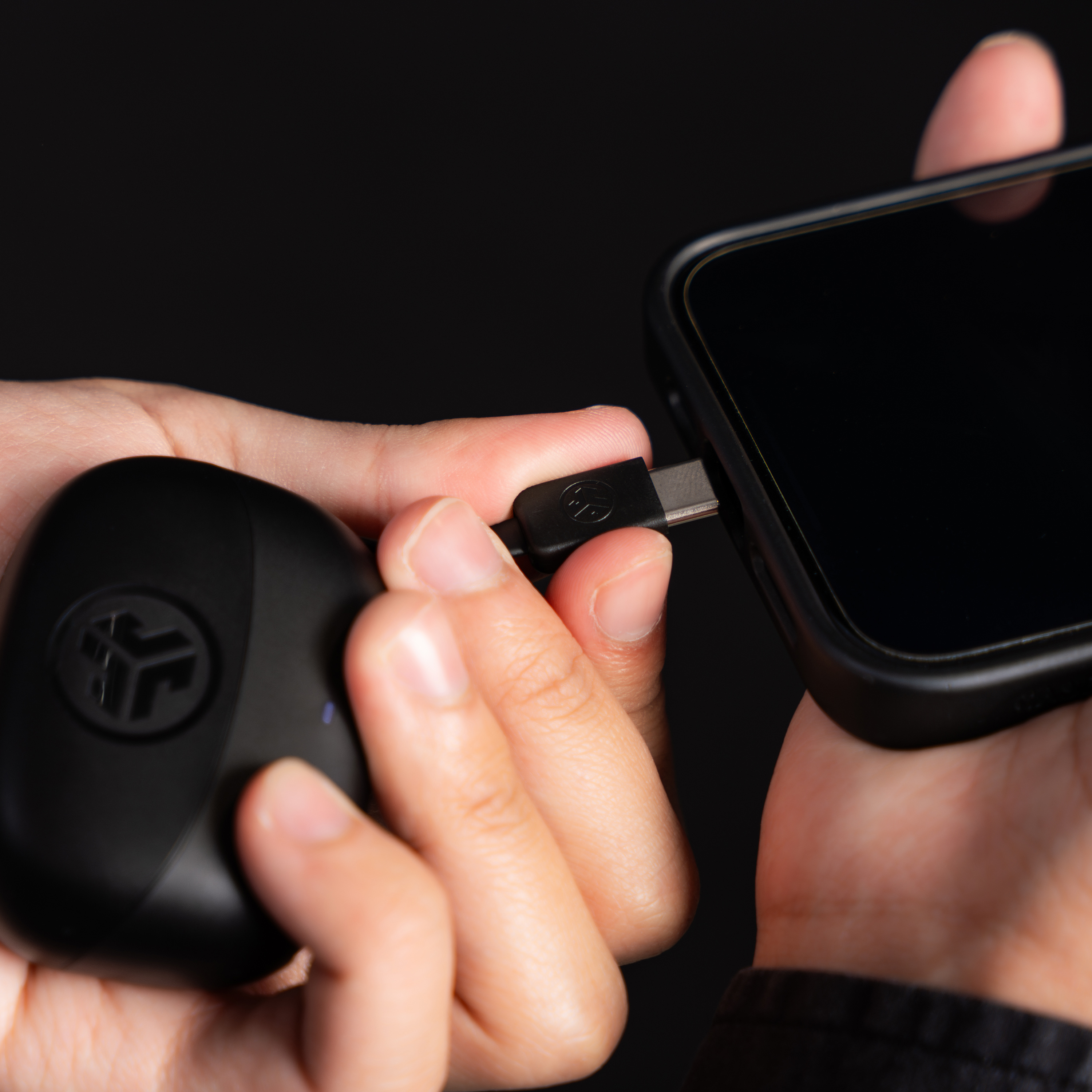 Eine Person verbindet ein USB-C-Kabel mit einem Smartphone. Eine schwarze Powerbank wird ebenfalls gehalten.