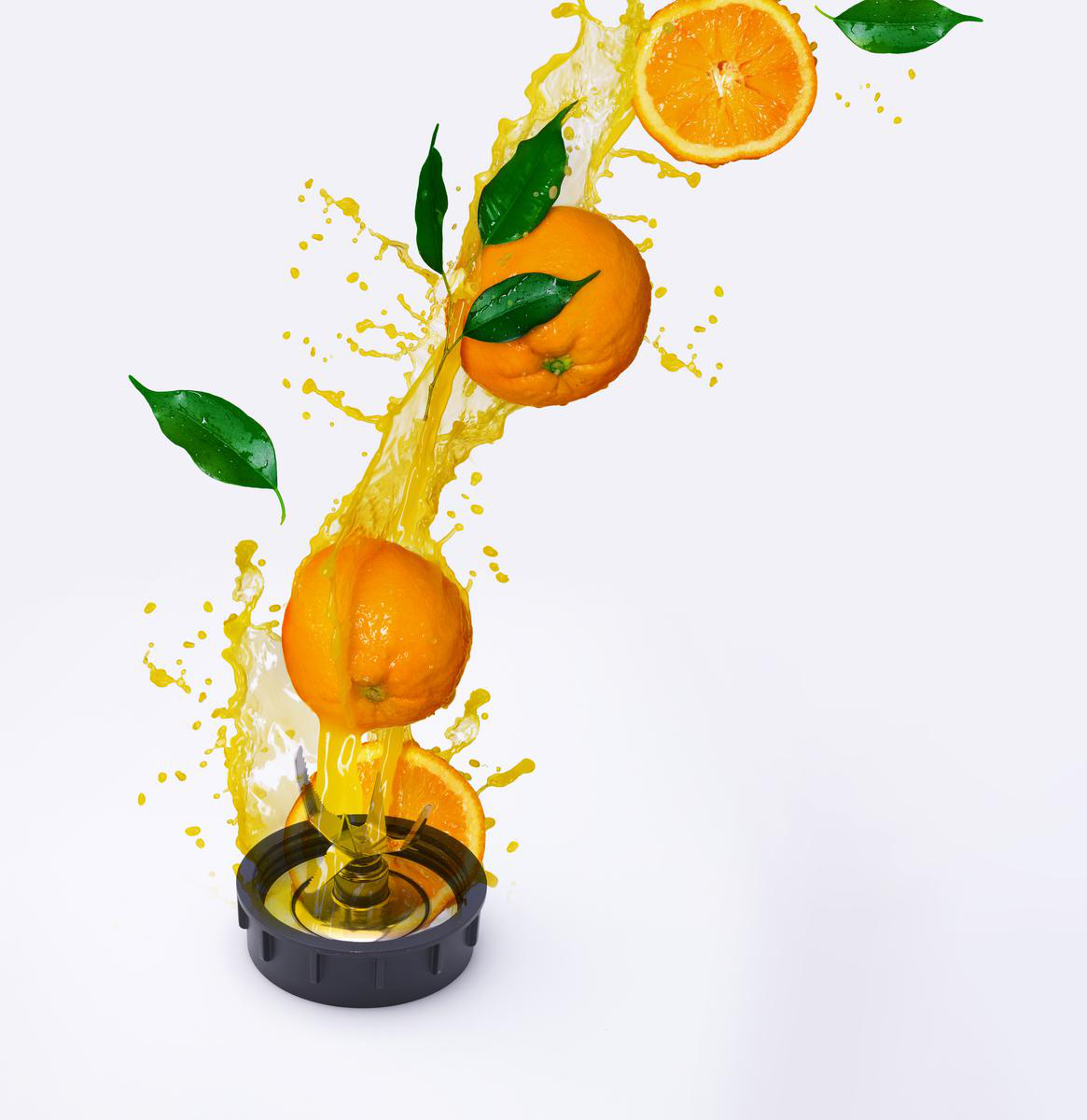 Orangen mit grünen Blättern und Orangensaft, der aus einem Mixer auf weißem Hintergrund spritzt.
