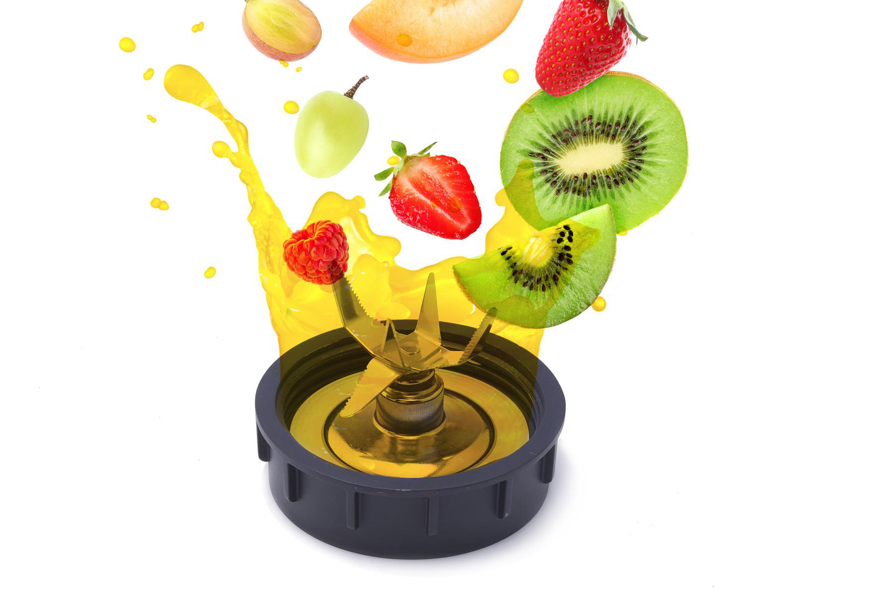 Ein Mixer mit Früchten wie Kiwi, Erdbeeren, Trauben und Himbeeren, mit gelbem Saft, der herausspritzt.