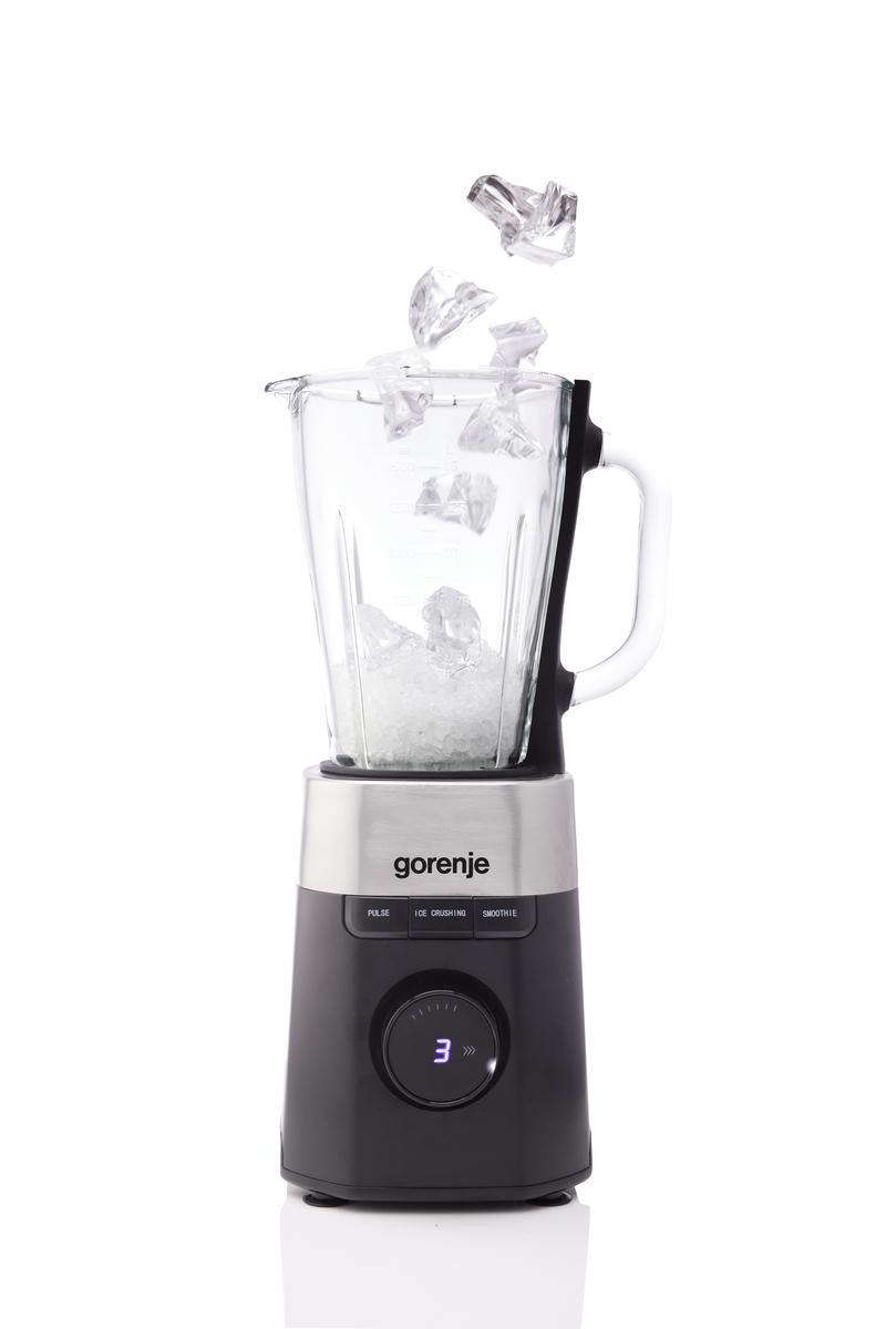 Ein Gorenje-Mixer, in den Eiswürfel fallen. Der Mixer ist schwarz und silber. Eis befindet sich bereits im Glas.