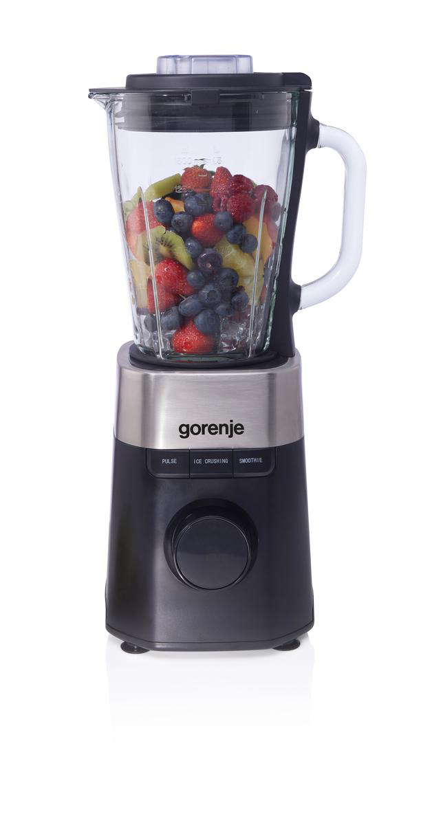 Mixer gefüllt mit Früchten: Erdbeeren, Blaubeeren, Kiwi und Himbeeren. Schwarze Basis, silberner Mittelteil und ein Glasbehälter. Weißer Griff.