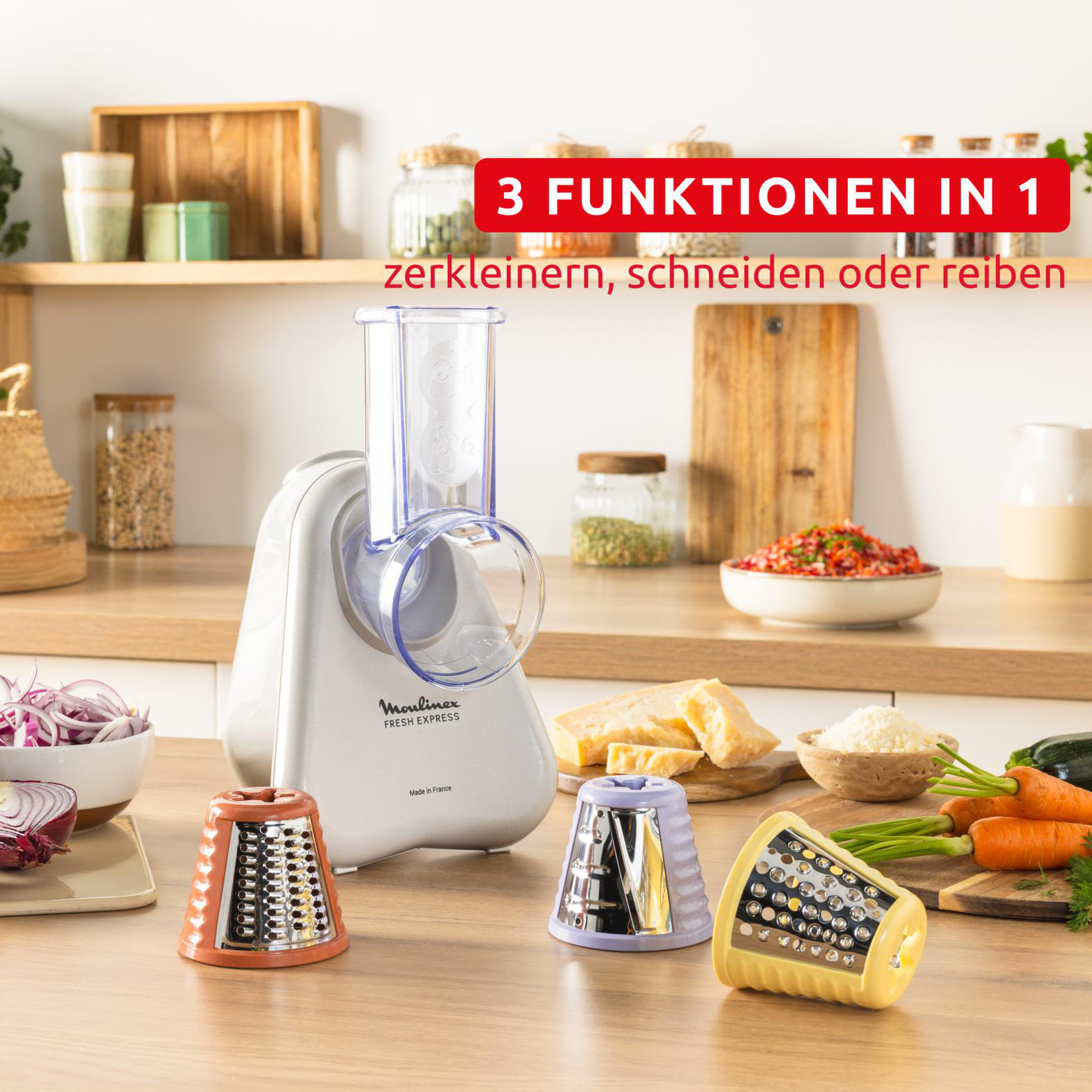 Ein Moulinex Fresh Express-Küchengerät mit drei farbigen Zerkleinerungskegeln, Gemüse und Käse auf einem Holztisch.