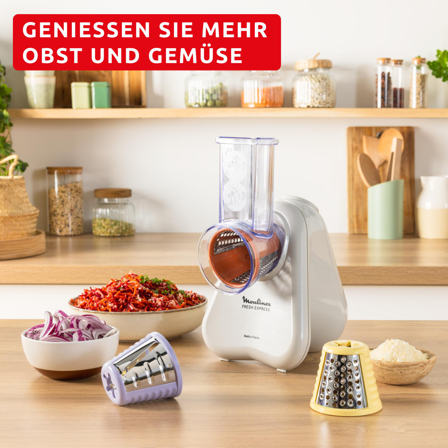 Ein Moulinex Fresh Express-Reibe mit gehacktem Gemüse und Zwiebeln. Verschiedene Reibeaufsätze sind vorhanden.
