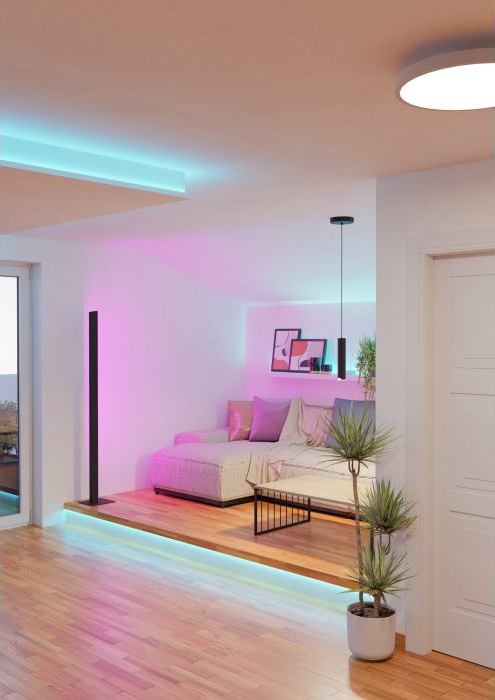Soggiorno moderno con divano, tavolino e piante. Luci rosa e blu illuminano lo spazio. Pavimento in legno e pareti bianche.