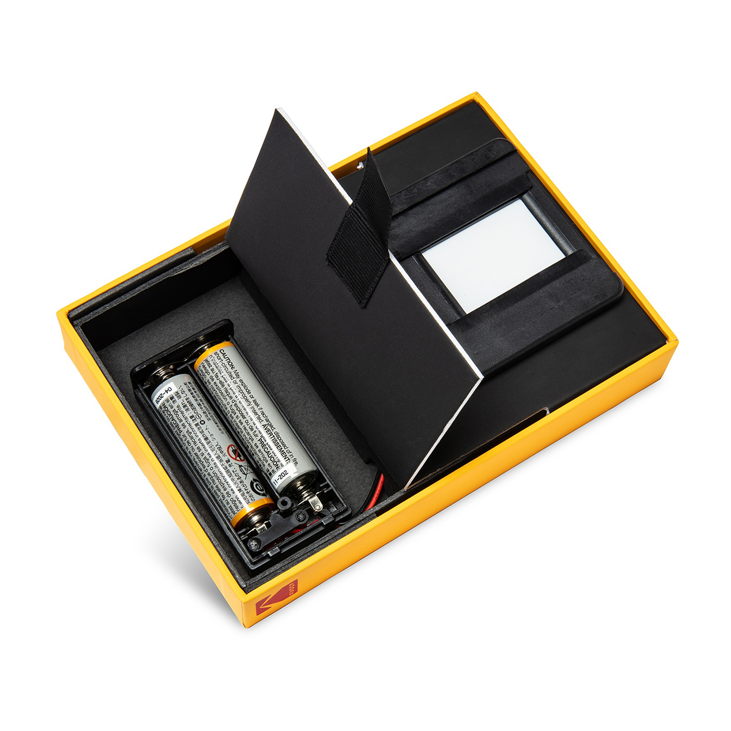 Scatola gialla aperta con batterie, schermo e componenti neri. Batterie nel vano sinistro. Schermo a destra.