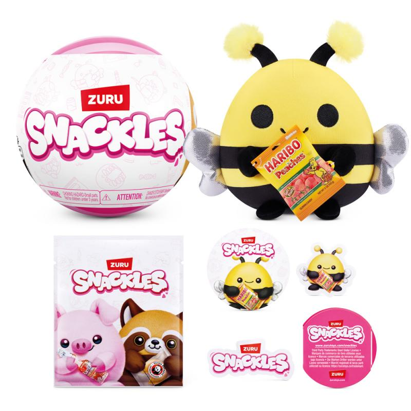 Das Bild zeigt eine ZURU Snackles-Kollektion. Es gibt einen rosa Ball, ein Bienenplüschtier mit Süßigkeiten und verschiedene Snackles-Verpackungen und -Aufkleber.