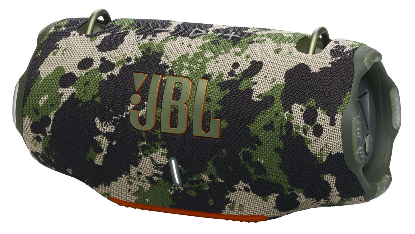 Głośnik JBL w kamuflażu. Ma zielone, czarne i beżowe wzory. Logo JBL jest pomarańczowe. Widoczne są metalowe pętle i przyciski.