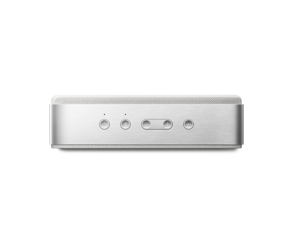 Egy ezüstszínű, téglalap alakú hangszóró előlapon négy gombbal: be/ki, bluetooth, hangerő le és fel, valamint fehér hálós tetővel.