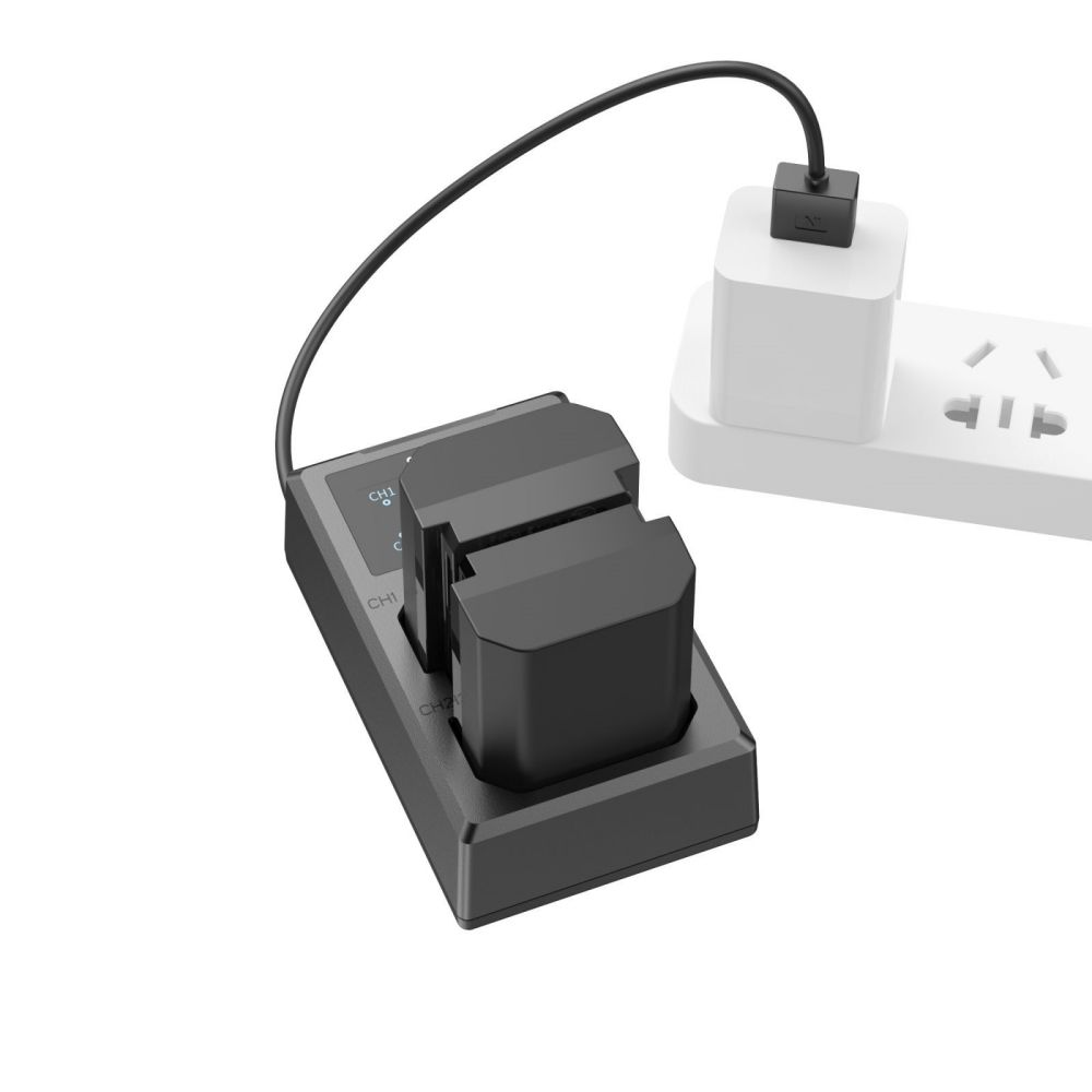 Chargeur de batterie noir branché sur une multiprise blanche. Le chargeur a deux fentes, un câble le relie à la multiprise.