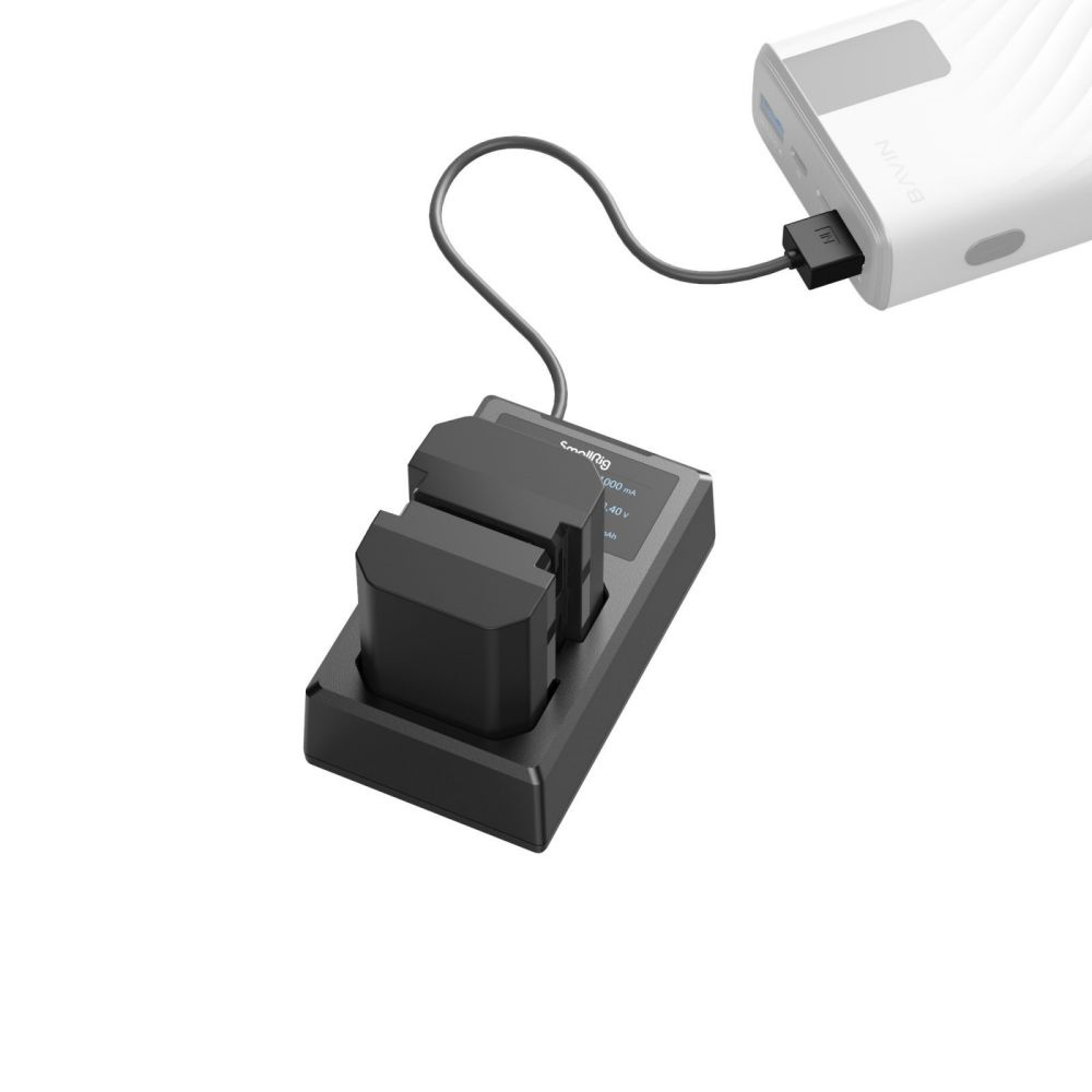 Un chargeur de batterie double SmallRig noir avec deux batteries connectées à une banque d'alimentation blanche via un câble noir.
