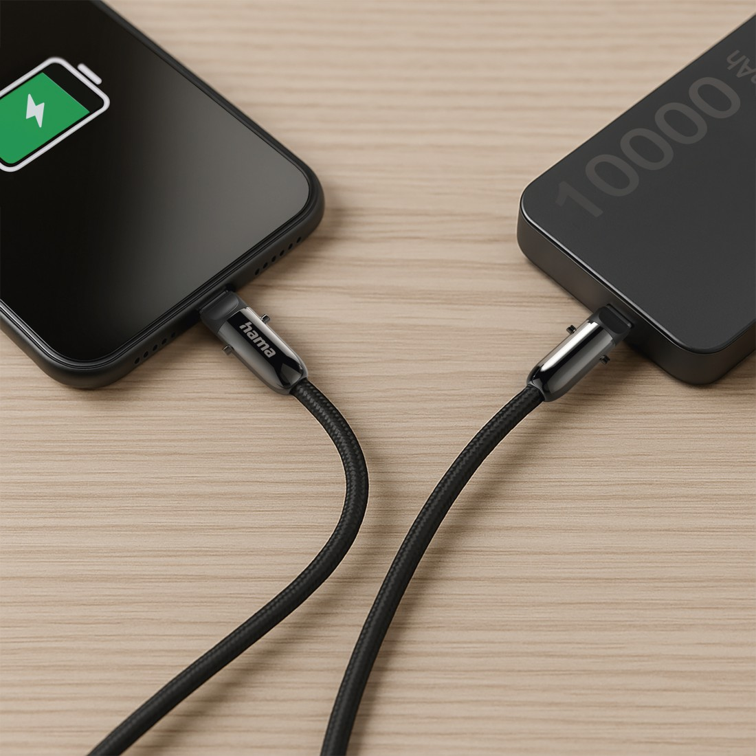 Ein Telefon und eine Powerbank sind über USB-Kabel verbunden und laden. Der Telefonbildschirm zeigt das Ladesymbol. Der Hintergrund ist Holz.