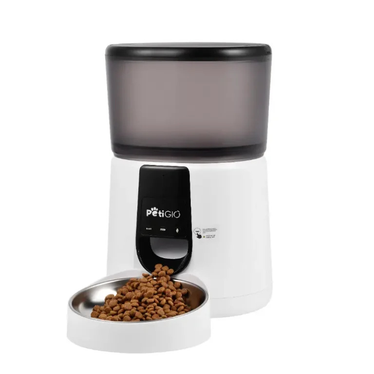 Biało-czarny automatyczny podajnik karmy dla zwierząt Petigio. Brązowa karma jest dozowana do miski ze stali nierdzewnej. Górny pojemnik jest szary.