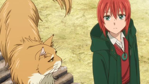 Anime-Szene. Ein rothaariges Mädchen in einem grünen Mantel steht neben einer großen orangefarbenen Katze. Die Katze ist auf einem Steinbauwerk.