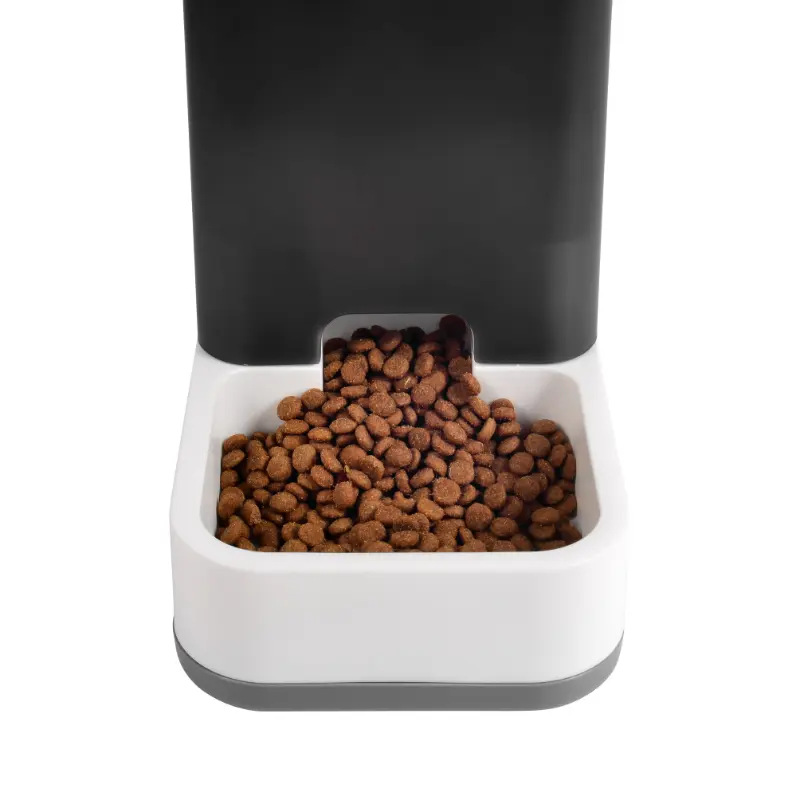 Dozownik karmy dla zwierząt z brązowymi krokietami wypełniającymi białą miskę. Górna część jest czarna.