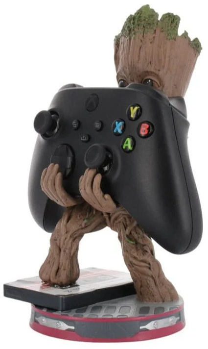 Groot figura egy Xbox kontrollert tart. Barna, zöld mohaszerű hajjal. A kontroller fekete.