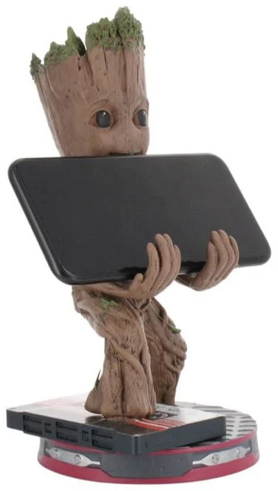 Groot figura egy fekete tabletet tart. A figura barna, tetején zöld levelekkel. Egy fekete és piros alapon áll.
