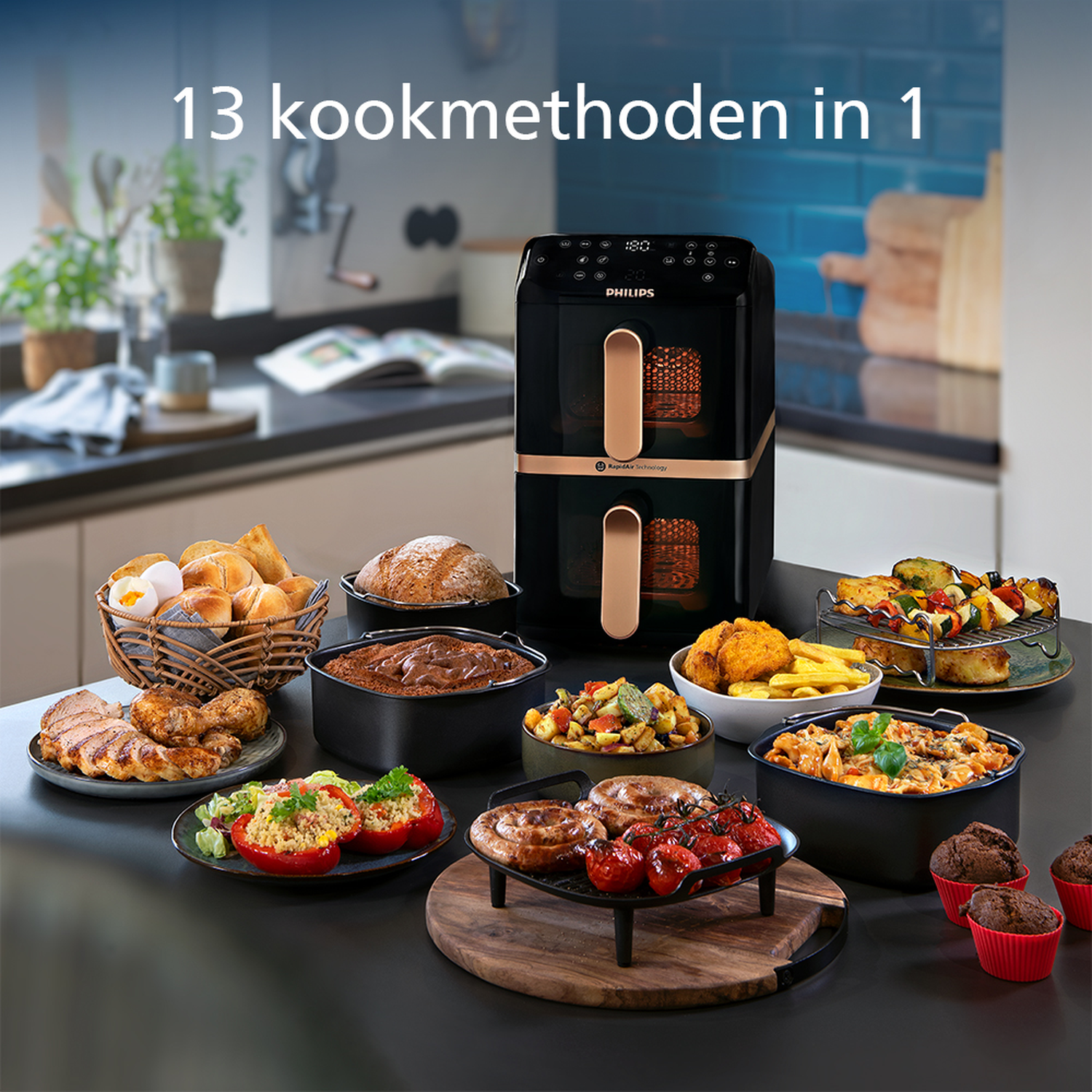 Een airfryer met verschillende gekookte gerechten: brood, vlees, groenten en muffins. De achtergrond toont een keuken met planten.