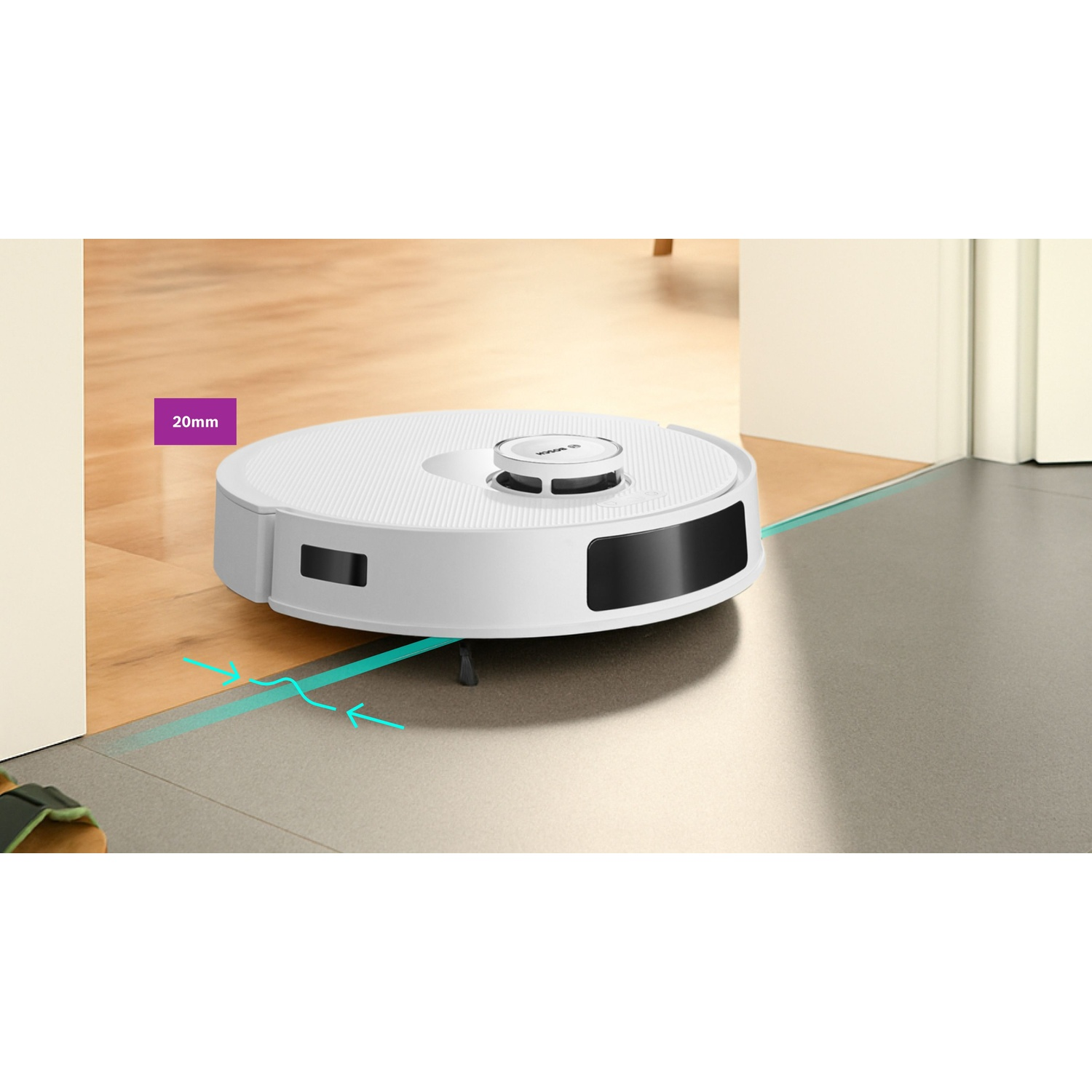 Un aspirapolvere robot bianco passa da un pavimento in legno a un pavimento in piastrelle grigie. Ha un sensore nero e un'etichetta da 20 mm.