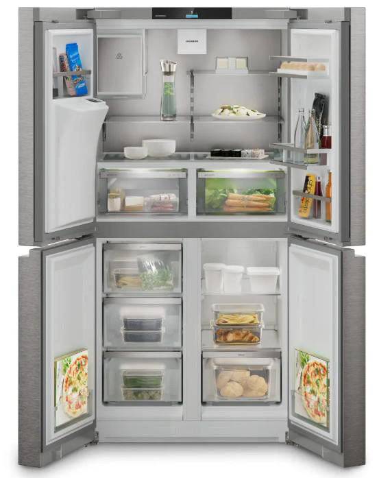 Geöffneter Edelstahlkühlschrank. Im Inneren sind verschiedene Lebensmittel auf Regalen und in Schubladen sichtbar, darunter Produkte, Getränke und Fertiggerichte.