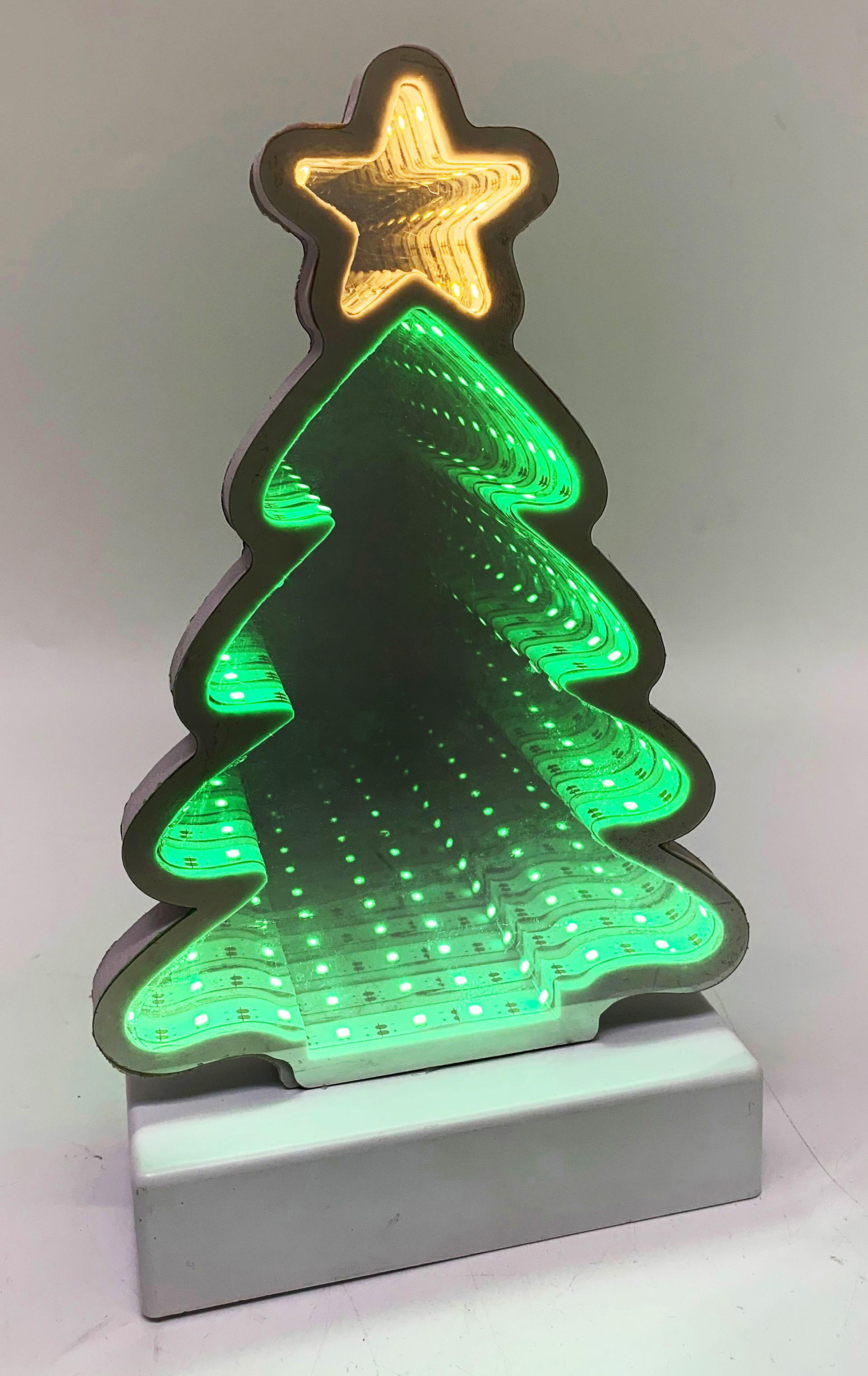 Ein weihnachtsbaumförmiges Licht mit einem Stern oben. Der Baum leuchtet grün und der Stern ist gelb. Es steht auf einem weißen Sockel.
