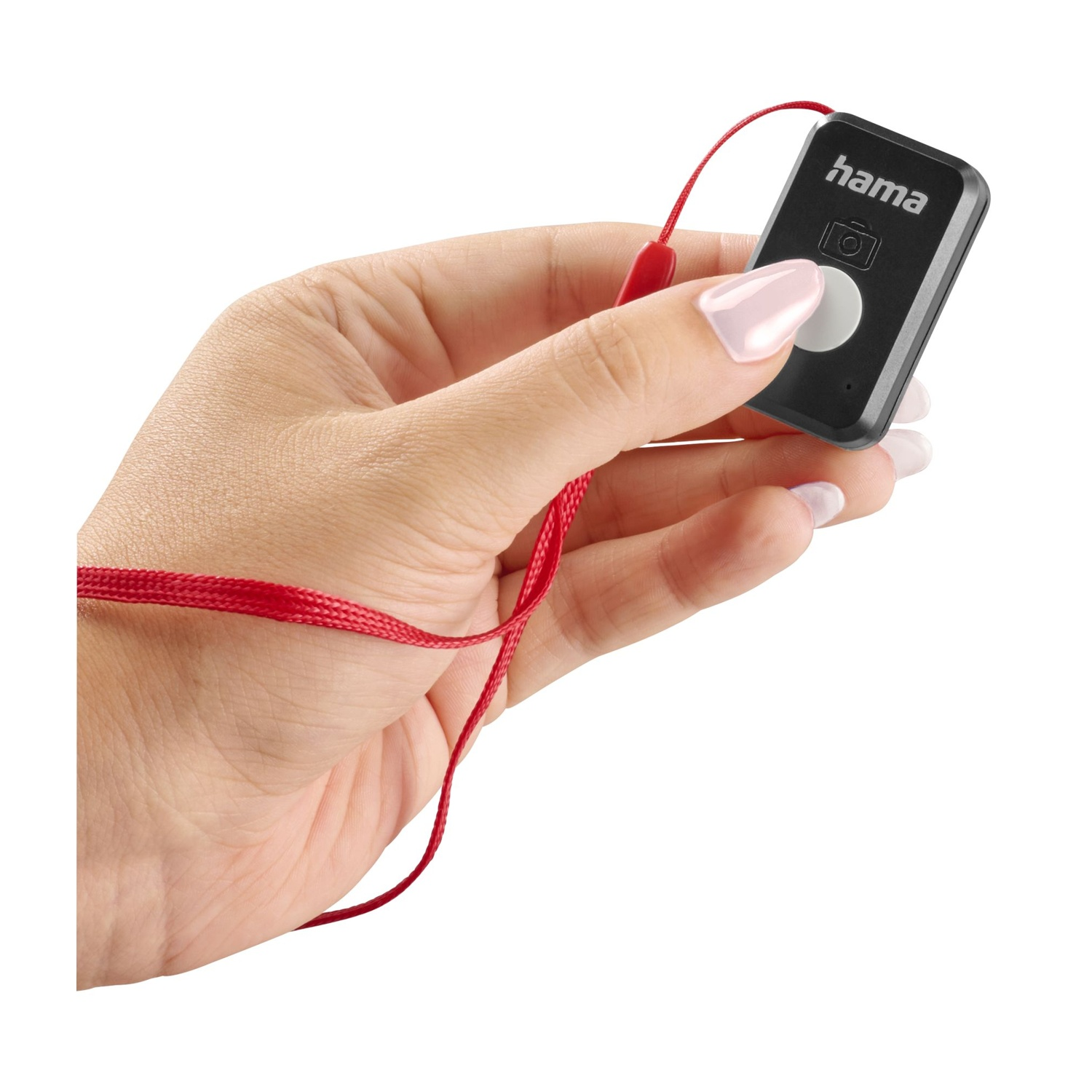 Una mano tiene un telecomando Hama nero con un cinturino rosso. Il telecomando ha un pulsante bianco. La mano ha lo smalto rosa.
