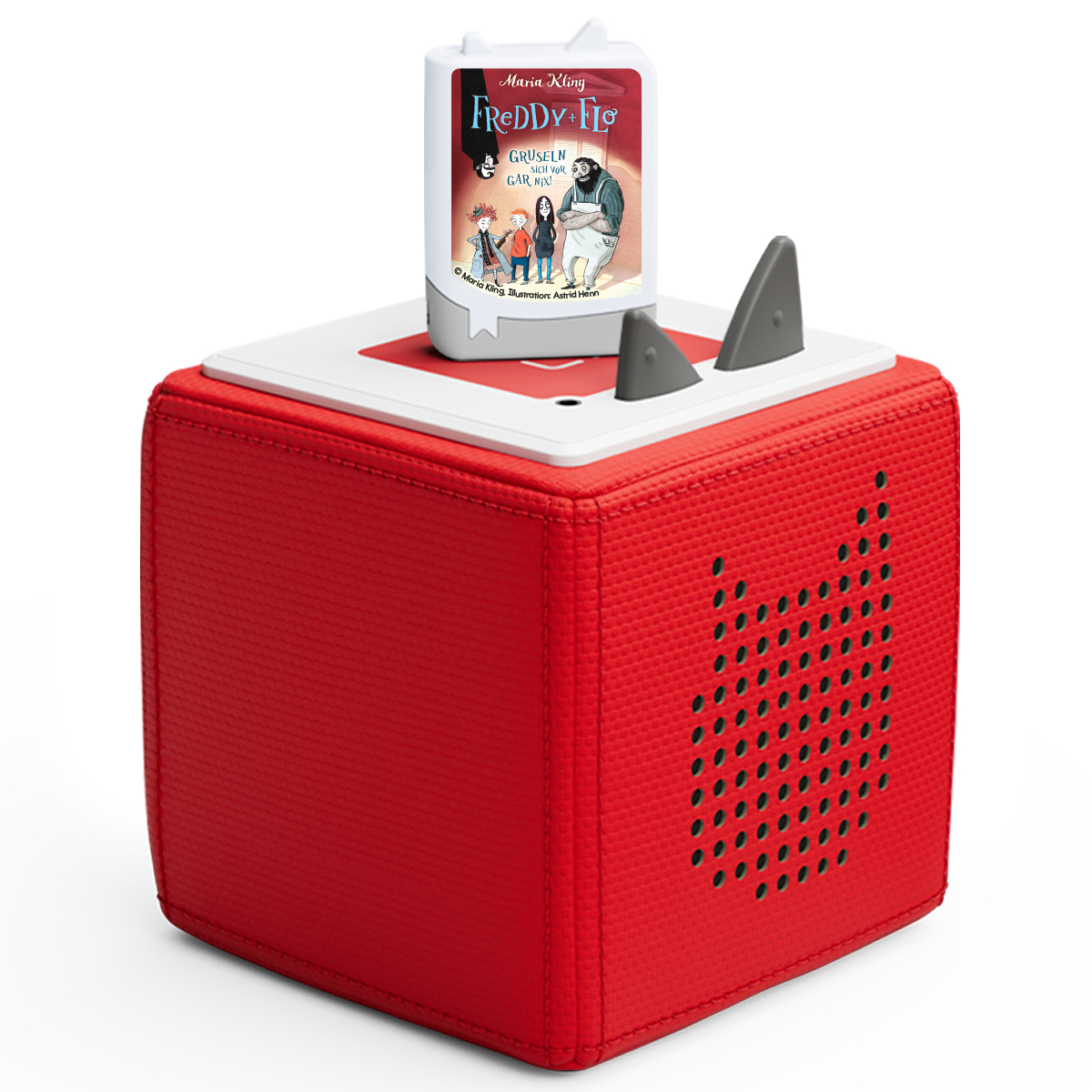 Ein roter Würfel-Lautsprecher mit weißer Oberseite. Ein Buch mit dem Titel 'Freddy & Flo' ist eingelegt. Graue Haifischflossen und schwarze Punkte sind sichtbar.