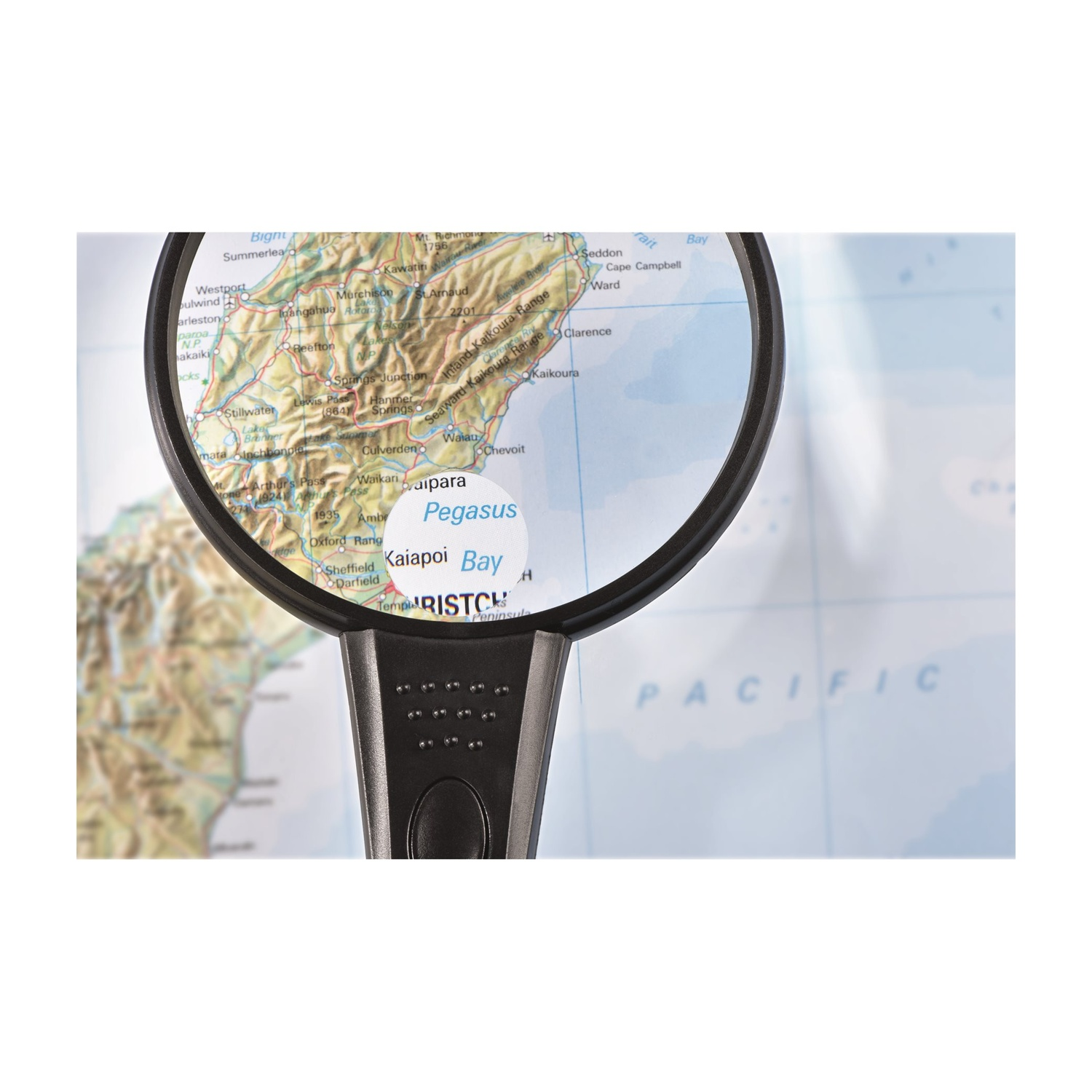 Una lente d'ingrandimento su una mappa, incentrata sulla regione di Pegasus Bay in Nuova Zelanda. L'oceano Pacifico è visibile sullo sfondo.