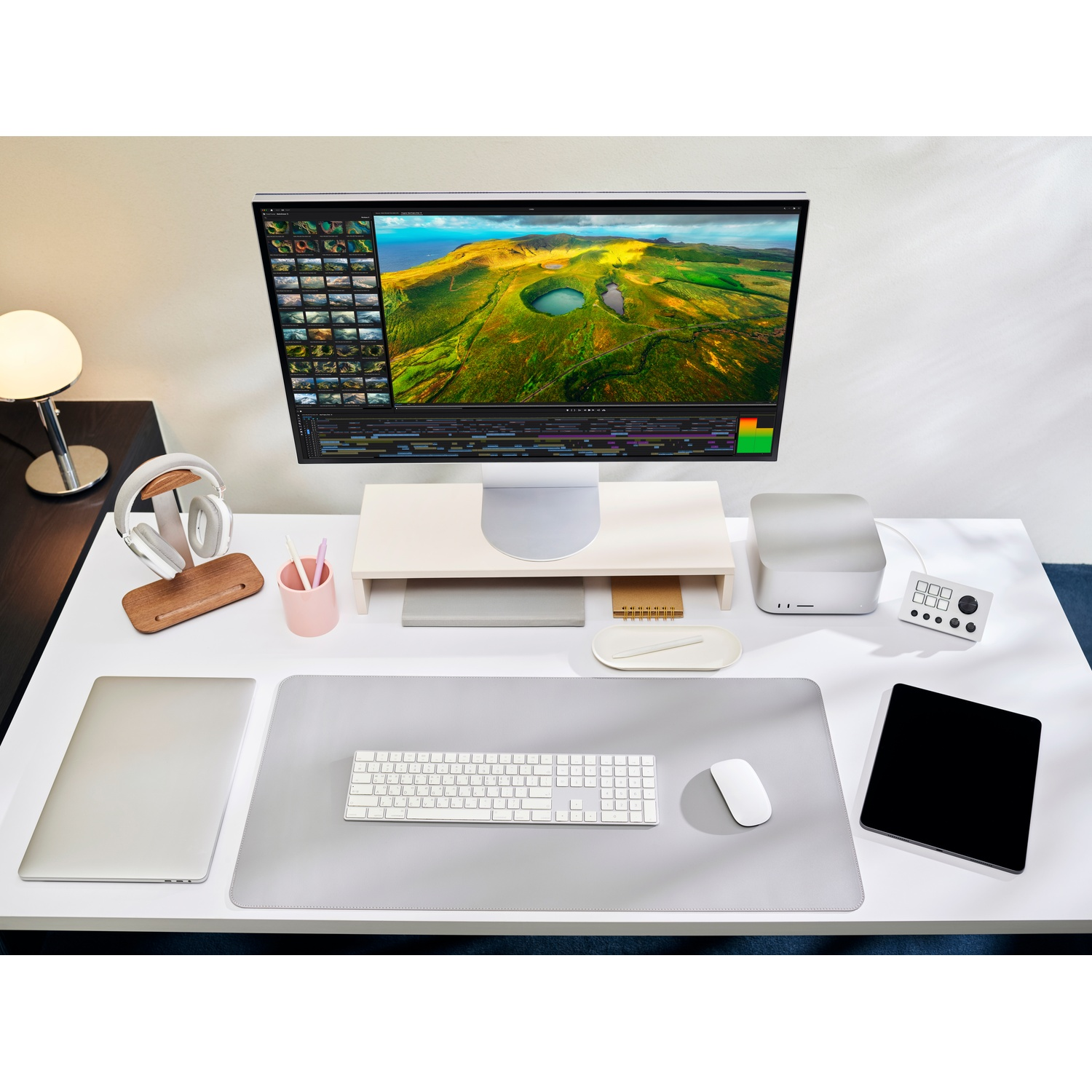 Une configuration de bureau moderne comprend un grand écran affichant un paysage, ainsi qu'un clavier, une souris, une tablette et d'autres appareils.