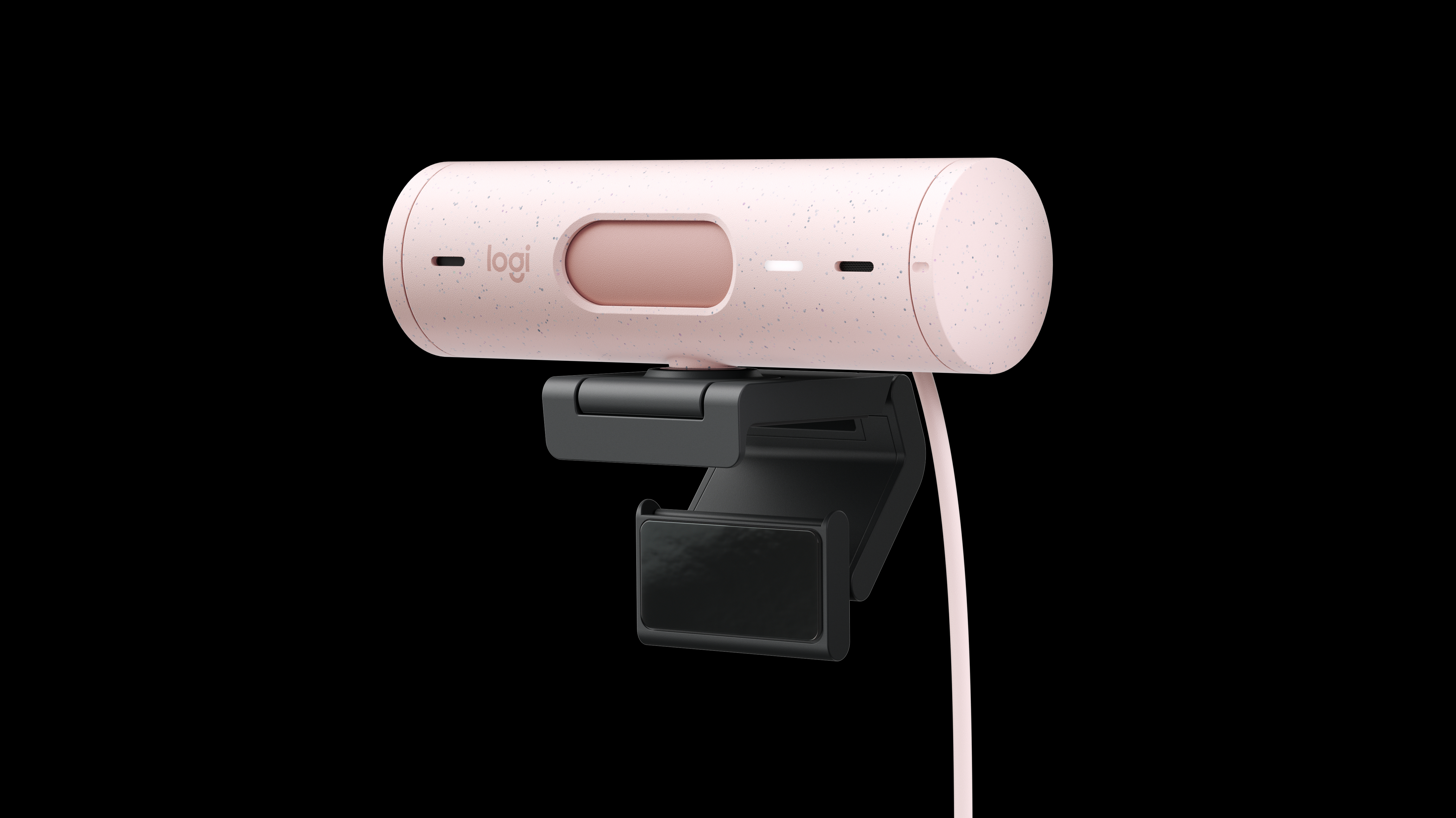 Eine rosa gesprenkelte Logitech-Webcam mit schwarzer Halterung. Die Webcam hat ein rosa Kabel und einen schwarzen Hintergrund.
