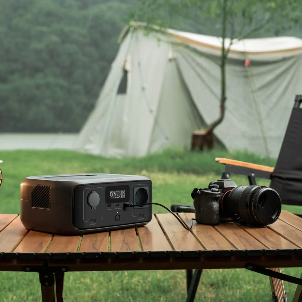 Una escena de camping con una central eléctrica, cámara y tienda de campaña. La central eléctrica está en una mesa de madera, con una cámara. Una tienda de campaña está al fondo.