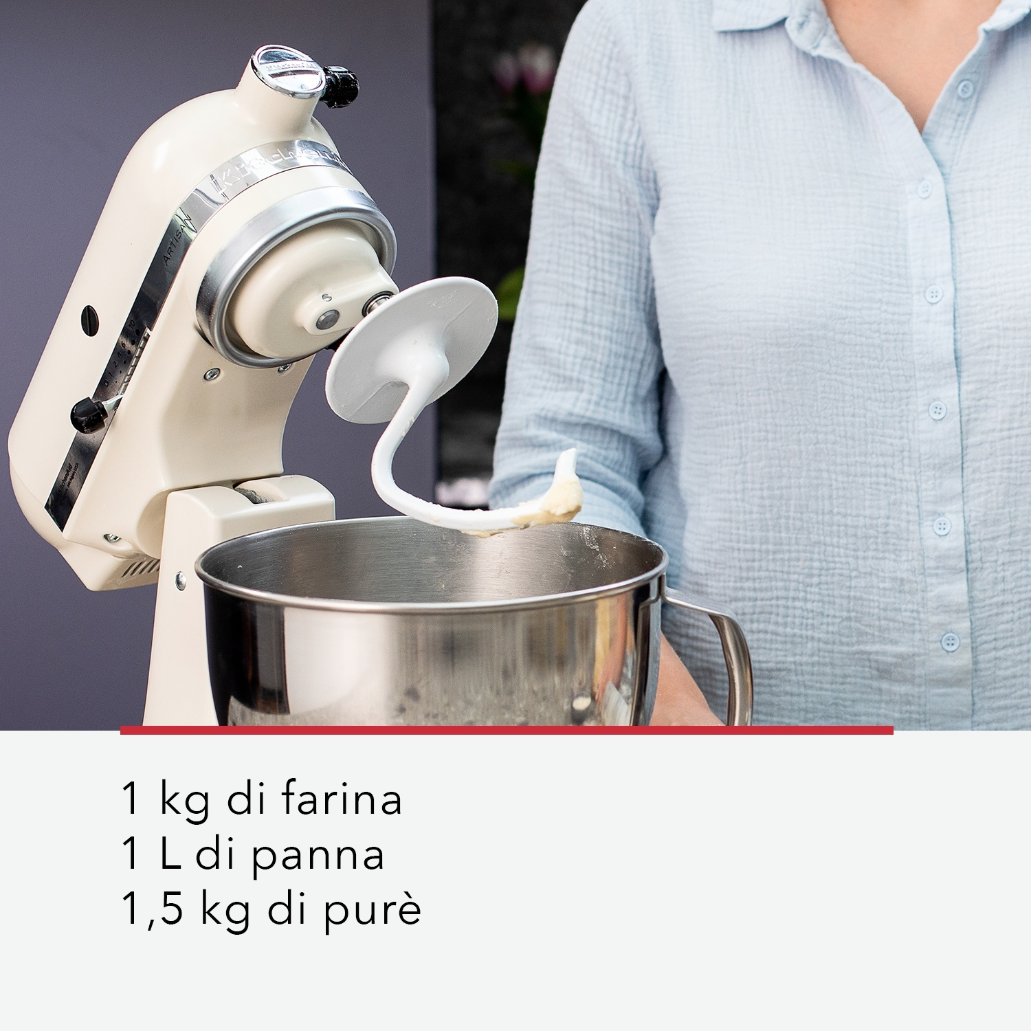 Un mixer KitchenAid color crema con gancio impastatore, ciotola e ingredienti. Una persona con una camicia azzurra tiene la ciotola.