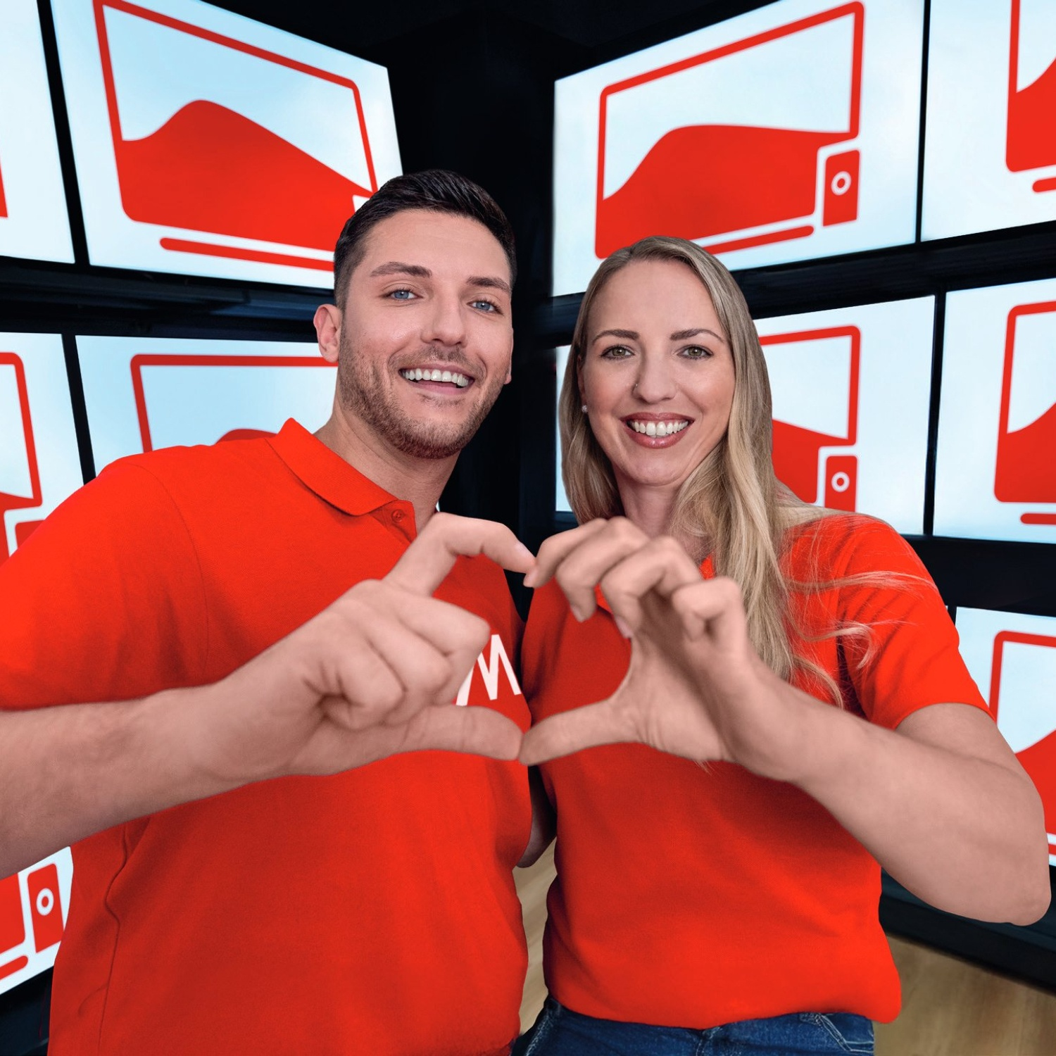 Un uomo e una donna con camicie rosse formano un cuore con le mani. Lo sfondo mostra loghi rossi simili a televisori.