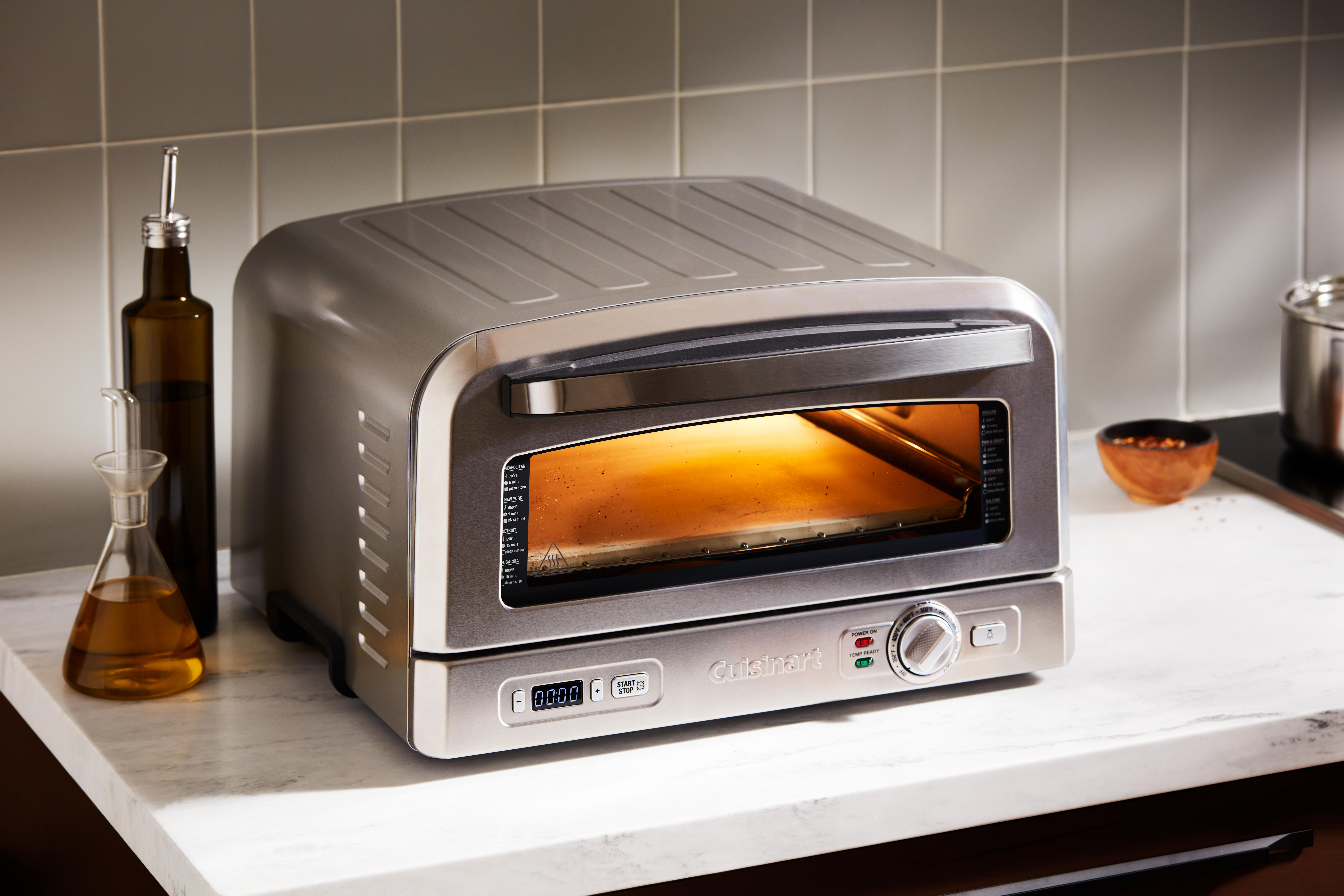 Ein Edelstahl-Cuisinart-Toaster steht auf einer weißen Arbeitsplatte. Olivenöl und ein Topf sind im Hintergrund.