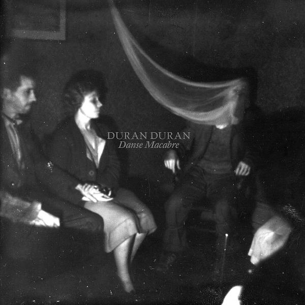 Vintage Schwarz-Weiß-Foto mit drei Personen. Ein Schleier schwebt über dem Kopf einer Person. Die Worte "Duran Duran" sind sichtbar.