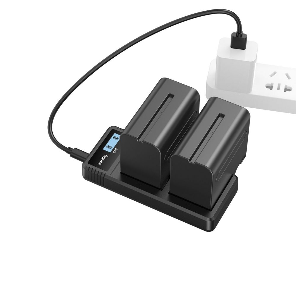 Un chargeur de batterie noir avec deux batteries, connecté à une prise de courant via un câble noir.