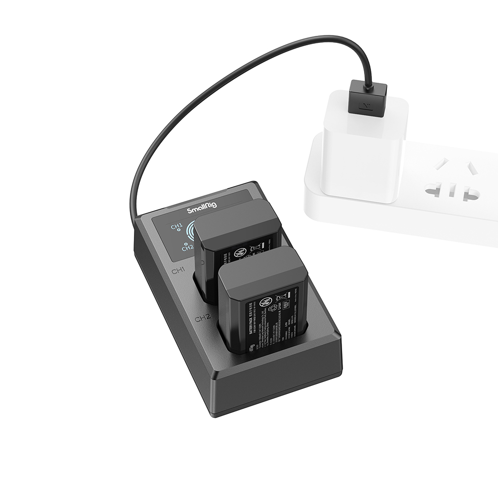 Un chargeur SmallRig noir avec deux batteries connecté à une prise de courant via un câble noir et un adaptateur blanc.